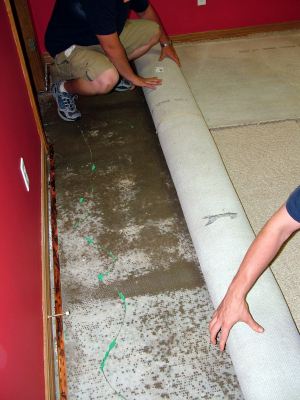 Waxahachie water damaged carpet being removed by two men.